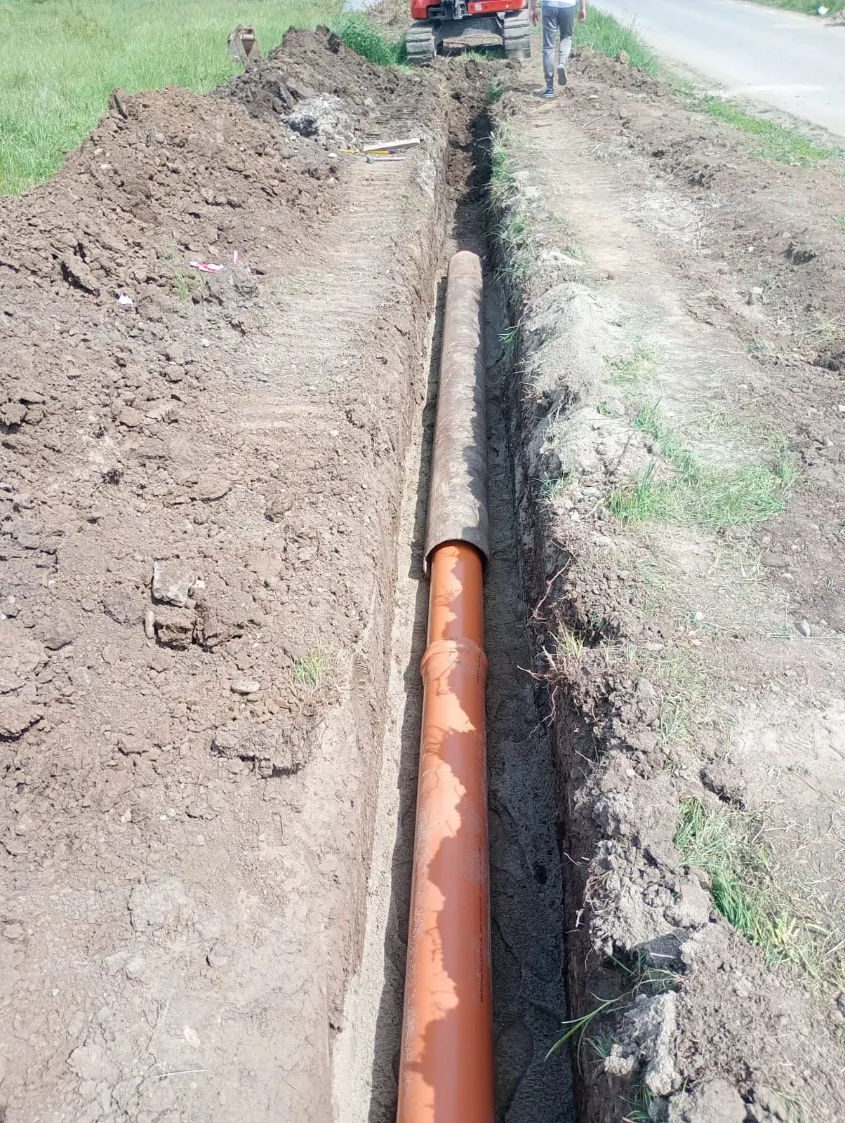 Conductă PVC pozată pe fundul tranșeei, pregătită pentru umplutură